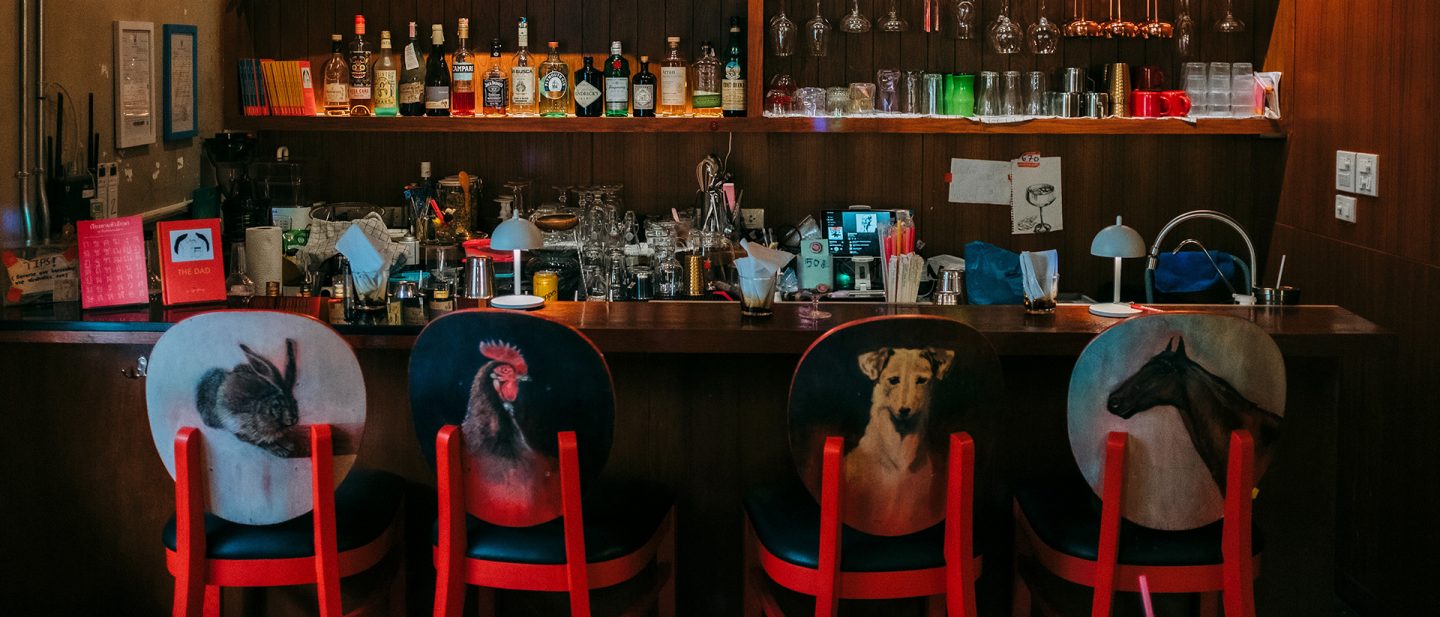 Interior view of Mischa Cheap bar with a counter full of bottles and four stools decorated with animal motifs