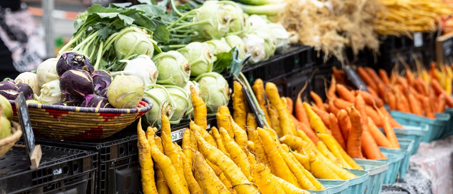 Photo of various fresh vegetables like carrots and kohlrabi displayed at a market in Mount Pleasant.