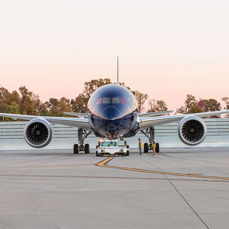Vooraanzicht van een donkerblauwe Lufthansa Boeing 787-9 op het asfalt, gesleept door een voertuig in de schemering