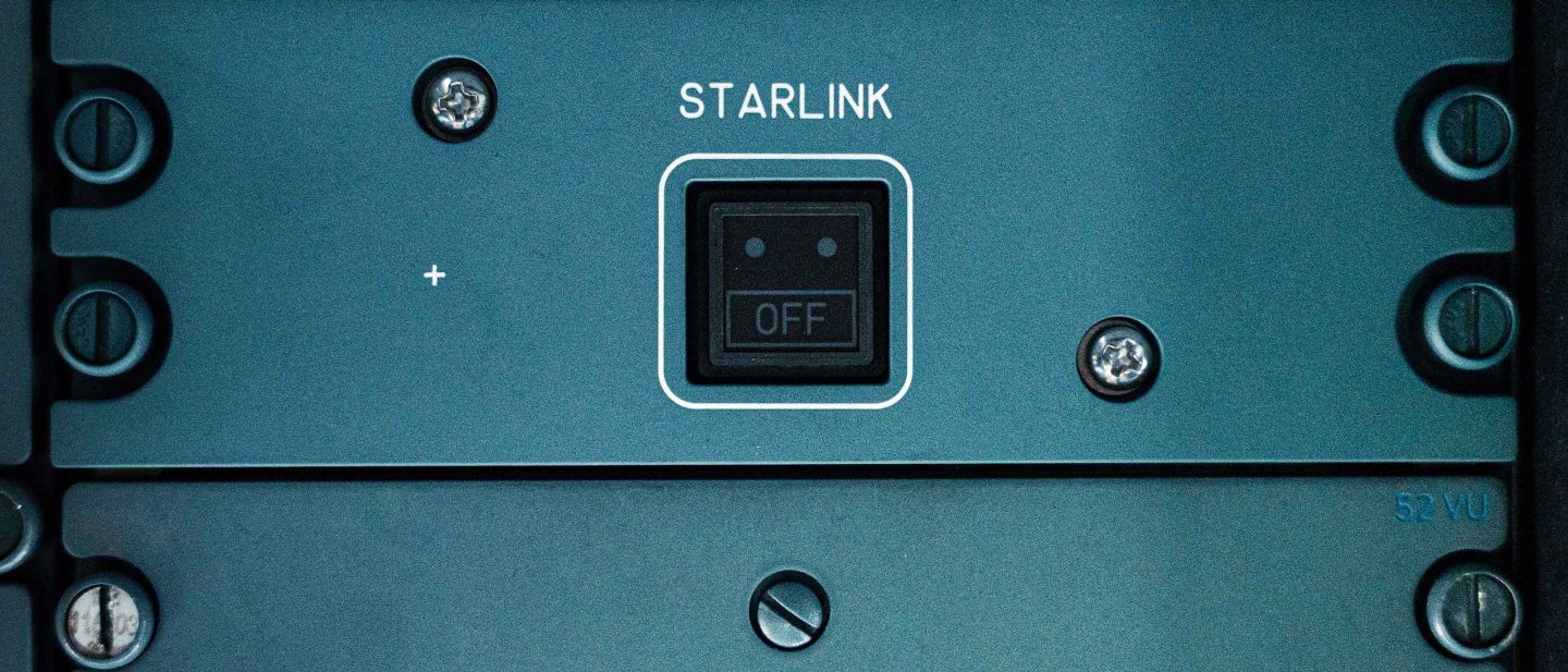 Close-up of hands installing a Starlink control panel into an electronics rack.
