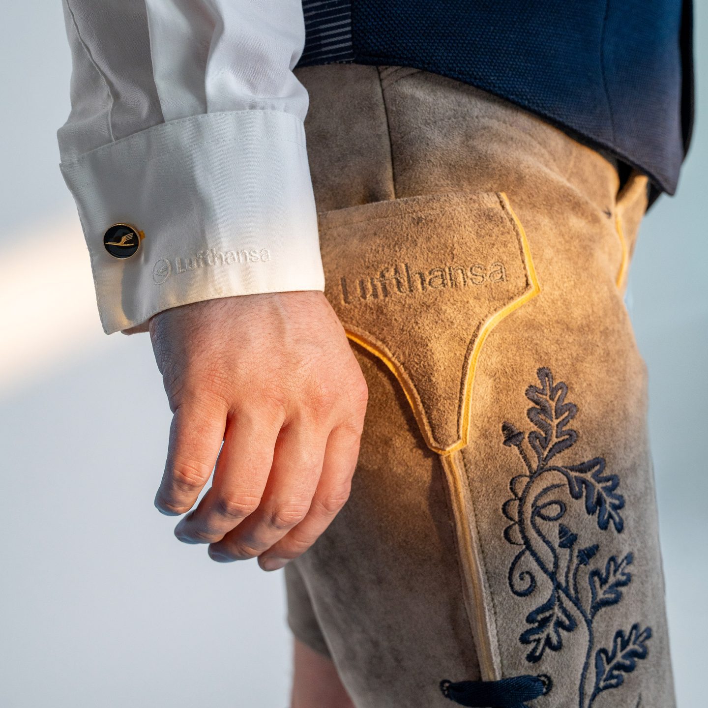 Close-up of traditional lederhosen with embroidery and a white shirt cuff with a cufflink