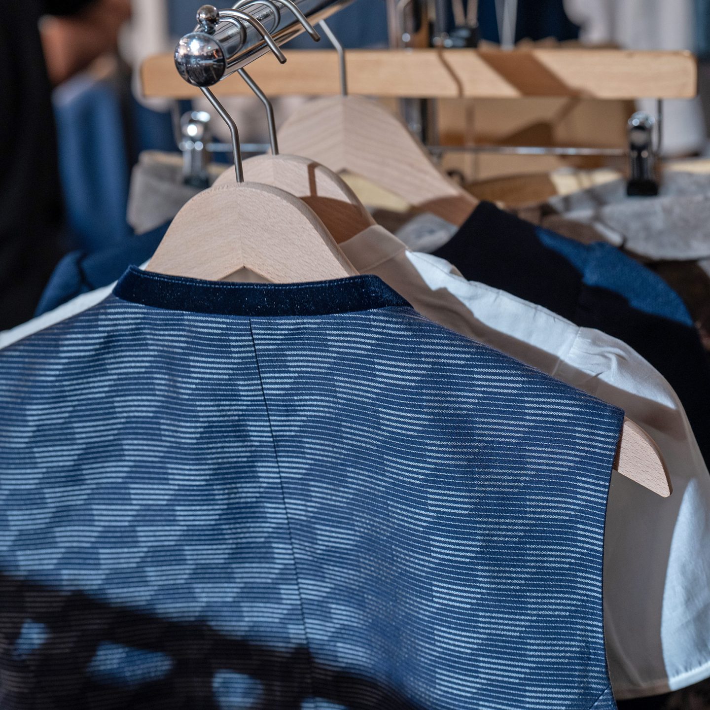Close-up of a patterned blue traditional vest hanging on a wooden hanger
