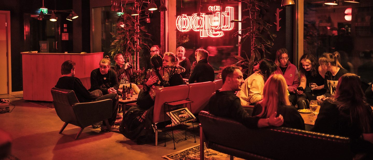 Vibrant bar scene with people socializing, neon lights, and cozy seating.