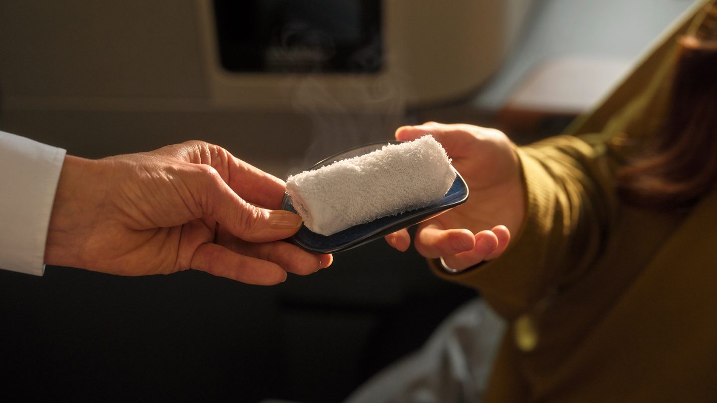 Hot towel is handed to a passenger on an airplane.