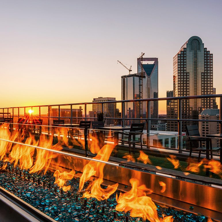 Rooftop bar Fahrenheit Charlotte with fire feature and view of Charlotte skyline at sunset