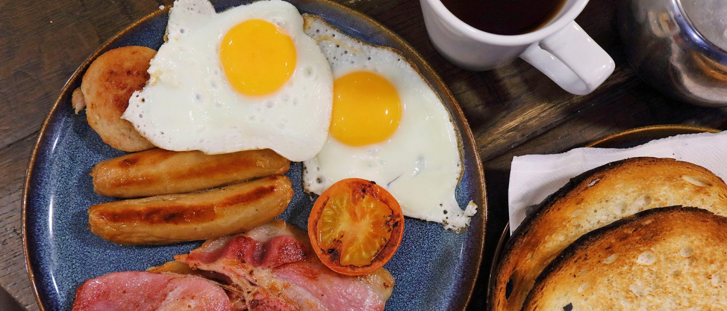 Traditional English breakfast with eggs, sausages, bacon, grilled tomato, and toast