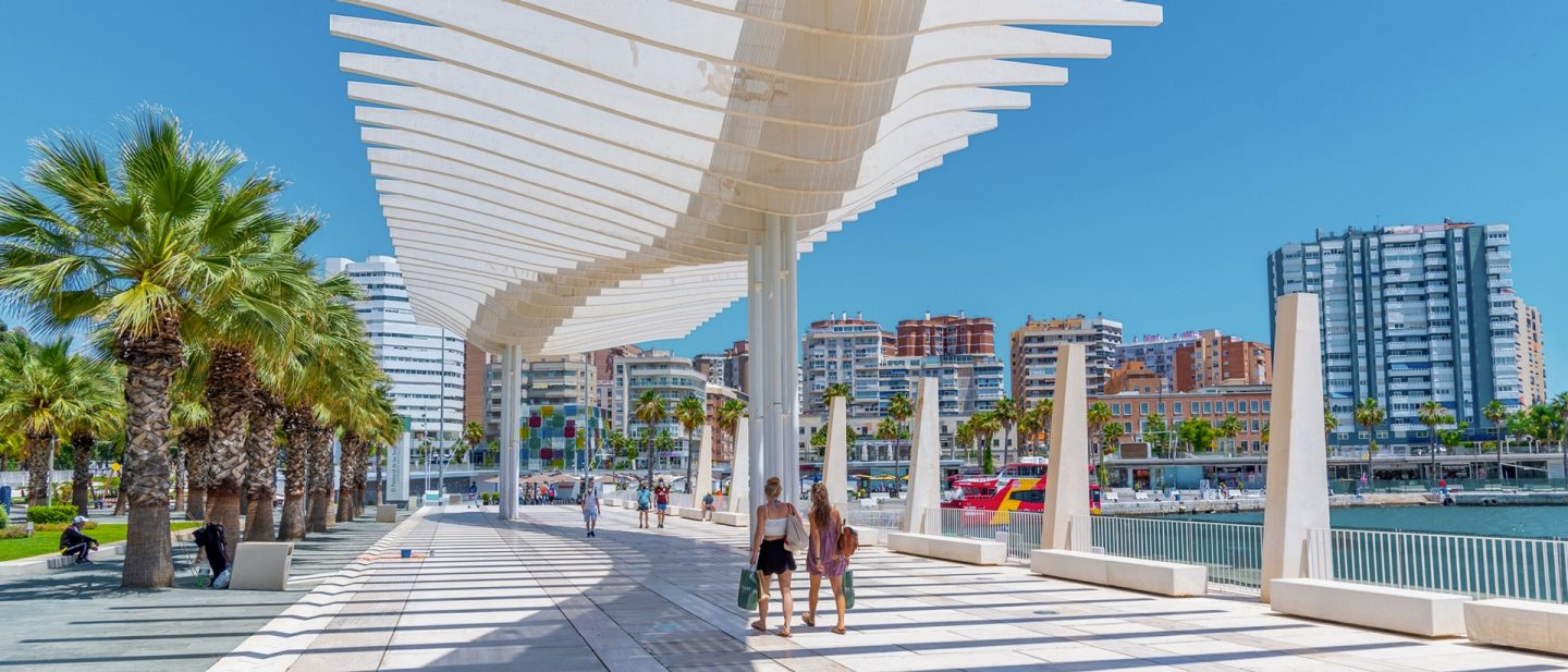 Moderne weiße Pergola am Hafen von Málaga mit Palmen und Spaziergänger:innen