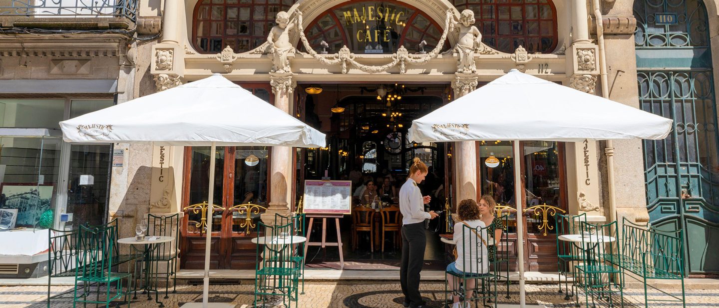 The Belle Époque façade of Café Majestic in Porto with guests under white umbrellas
