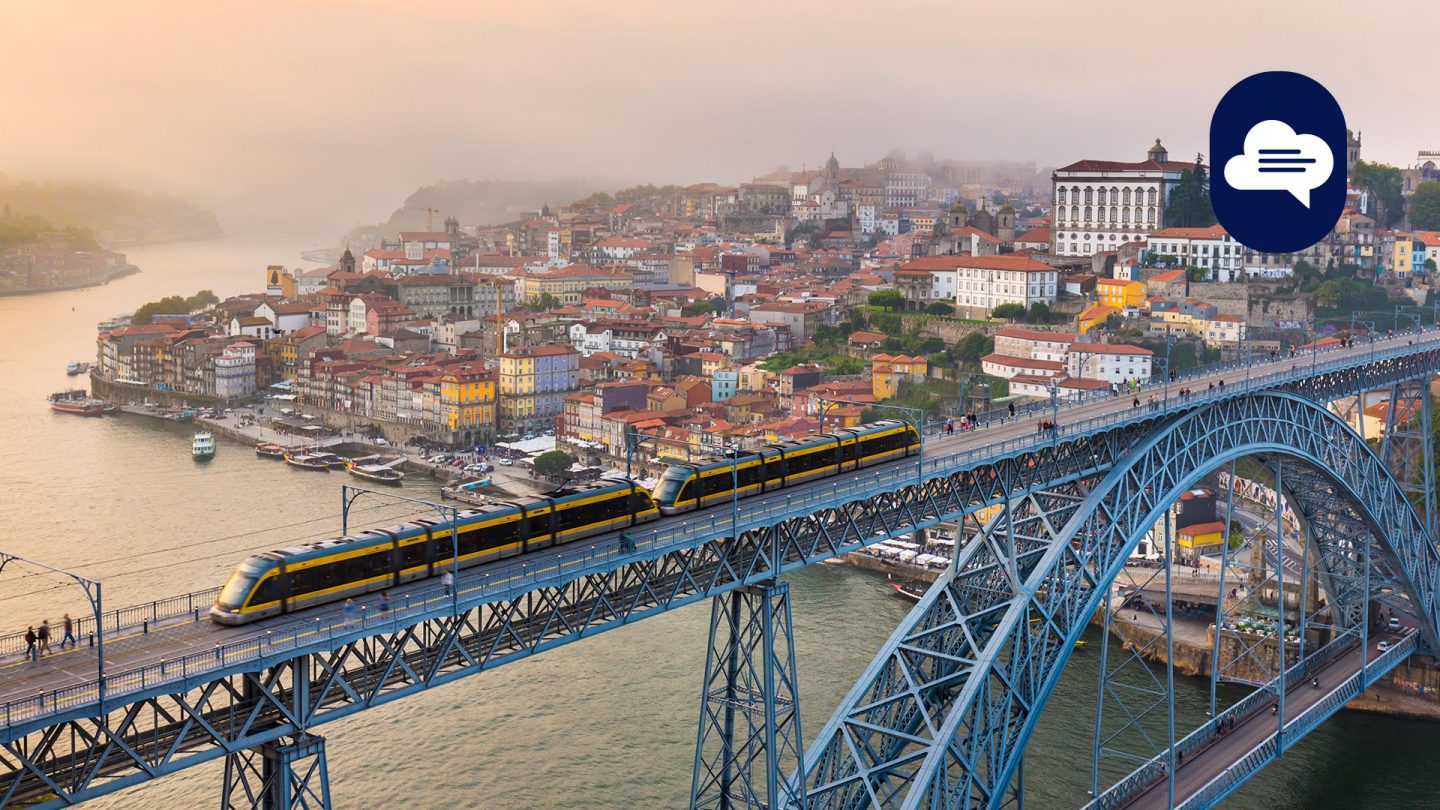 Yellow metro crosses the bridge over the Douro River, passing by Porto's old town