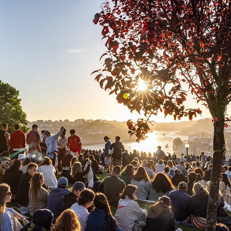 Crowd of people in a park at sunset overlooking a river and a city