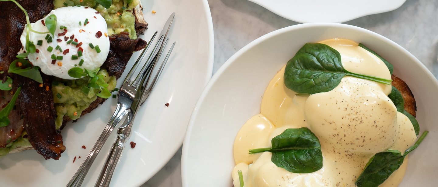 Breakfast with poached egg, avocado toast, and hollandaise sauce