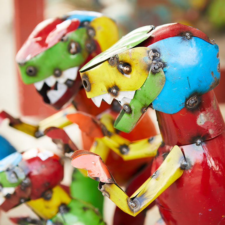 Close-up of colorful metal dinosaur sculptures with jagged teeth