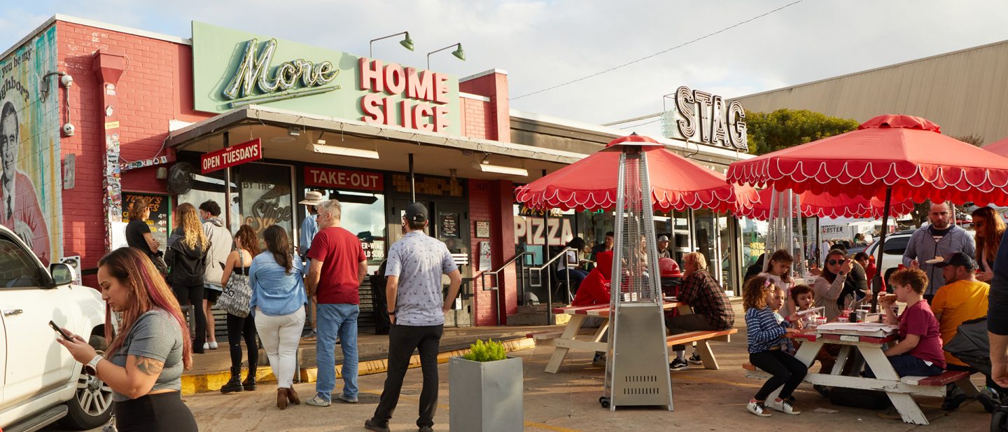 People in Austin, Texas, waiting in line in front of and sitting outside Home Slice restaurant