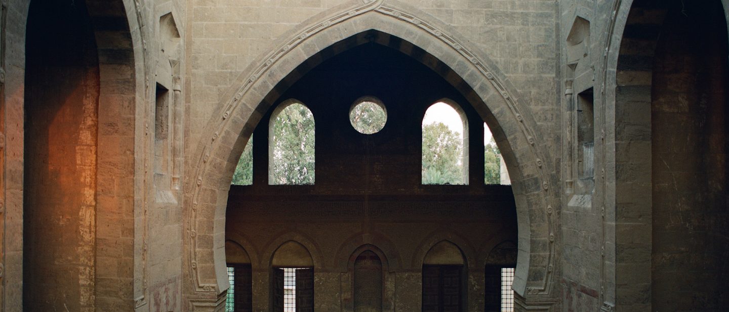 Interior view of a historic stone building featuring large, ornate pointed arches