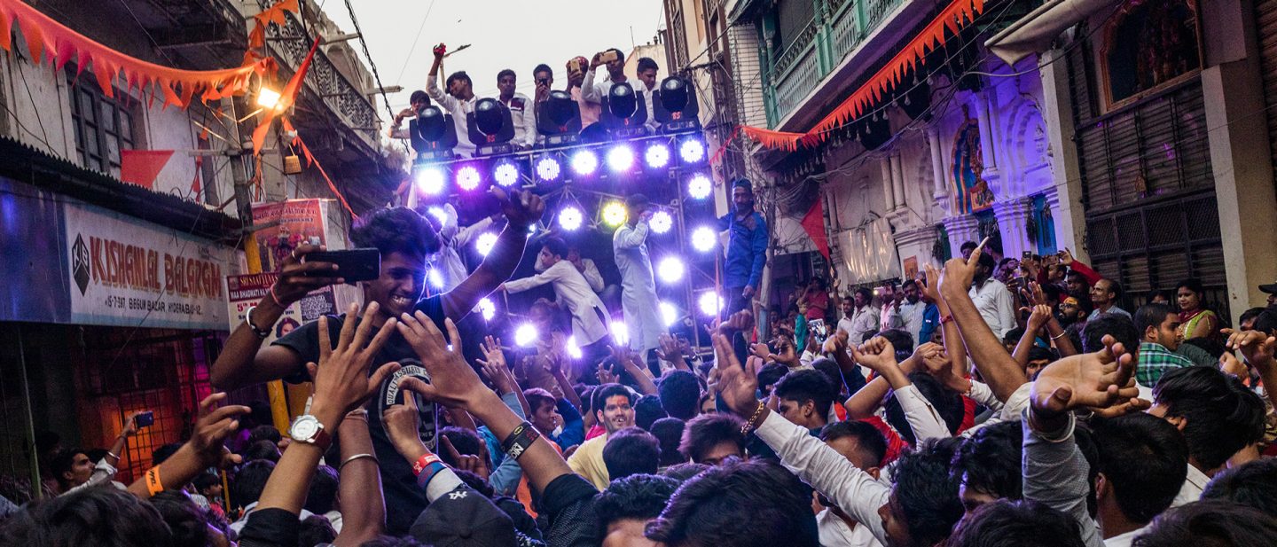 Crowd enjoying a lively street festival in India with lights and music.