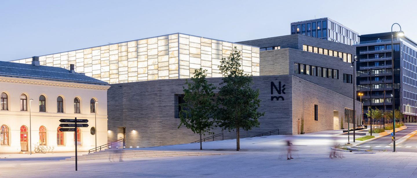 The exterior of the National Museum in Oslo features stone walls and a lit facade.
