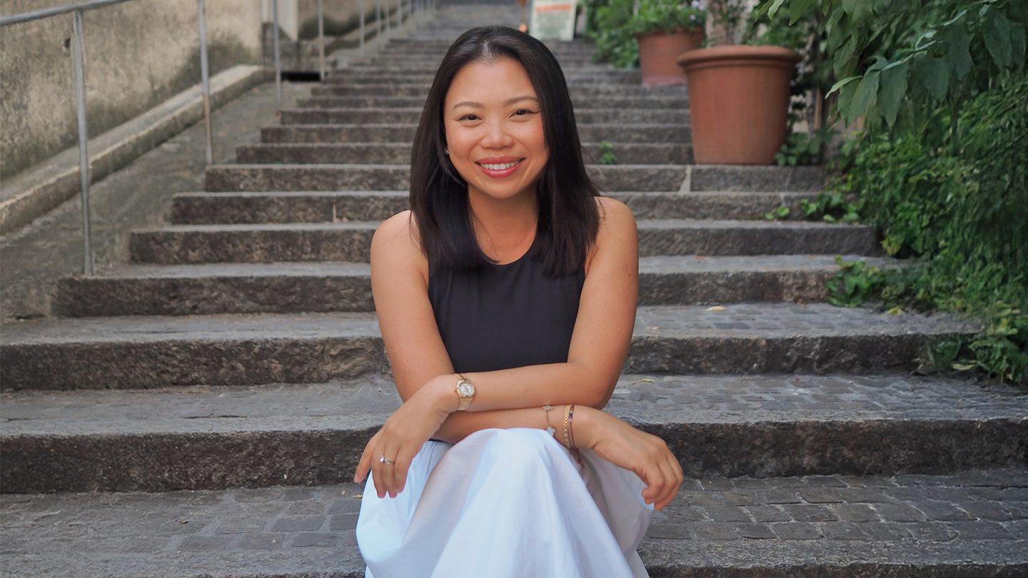 Content creator Carrie Meier Ho sitting on steps and smiling in an urban setting