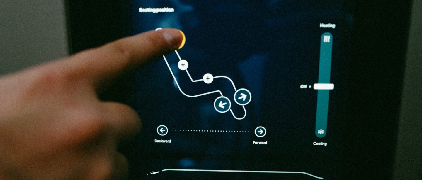 Close-up of a finger adjusting the seating position and temperature controls on a touchscreen in an airplane