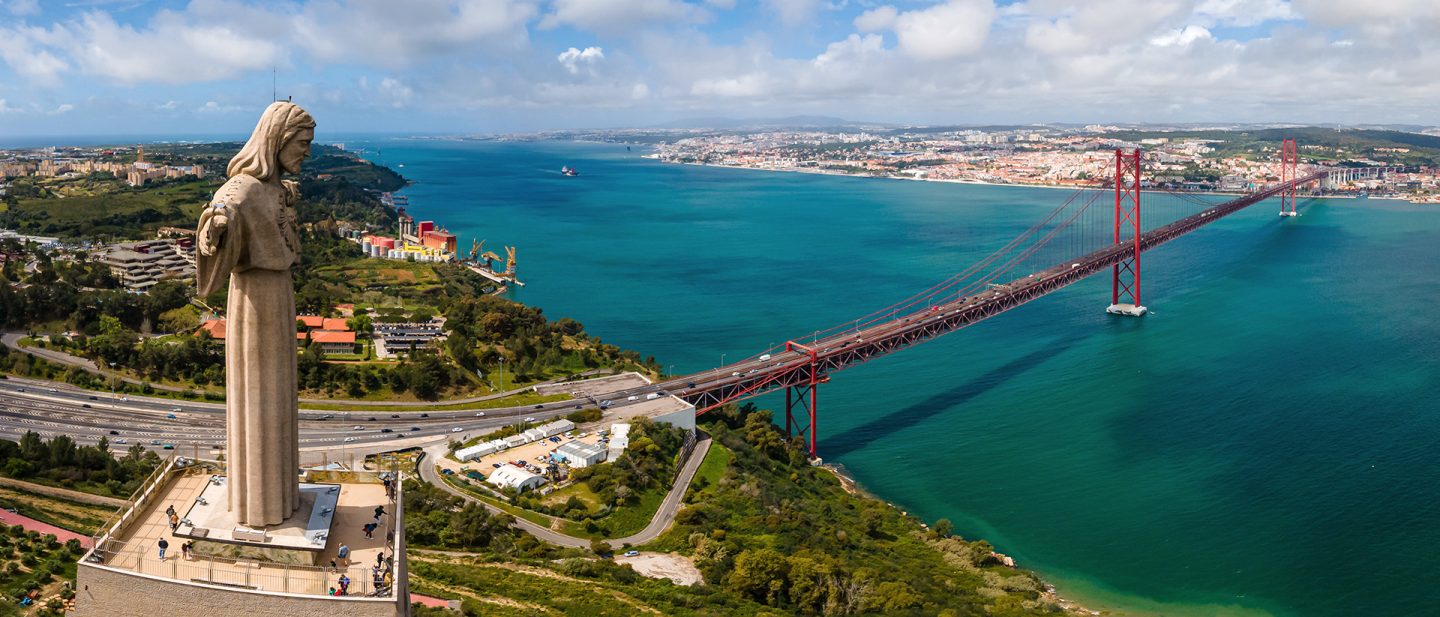 Eine Luftaufnahme der Statue Cristo Rei mit Blick auf die Brücke des 25. April und die Stadt Lissabon in Portugal.