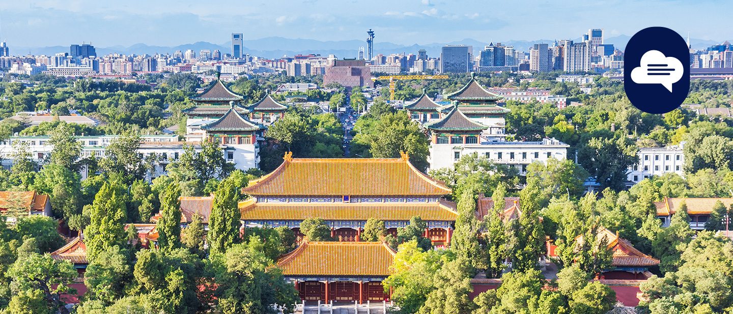 View over a historic palace complex in Beijing with the city's modern skyline in the background.
