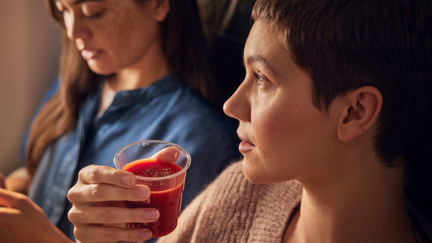 Frau im Flugzeug hält einen Becher Tomatensaft in der Hand