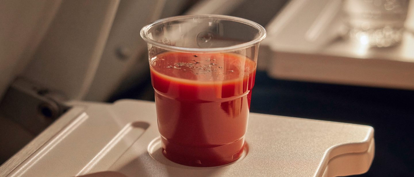 Ein Becher Tomatensaft mit Pfeffer auf einem Flugzeugtisch