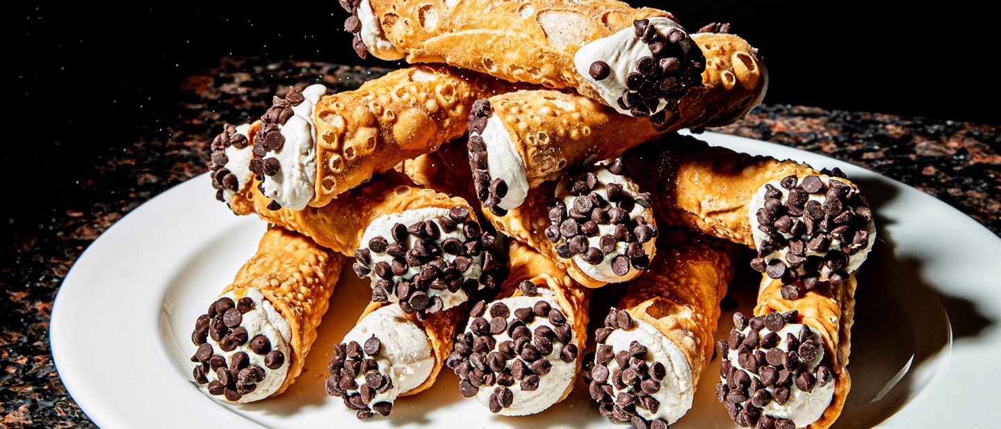 Ein Stapel Cannoli mit Ricotta-Füllung und Schokoladenstückchen auf einem weißen Teller