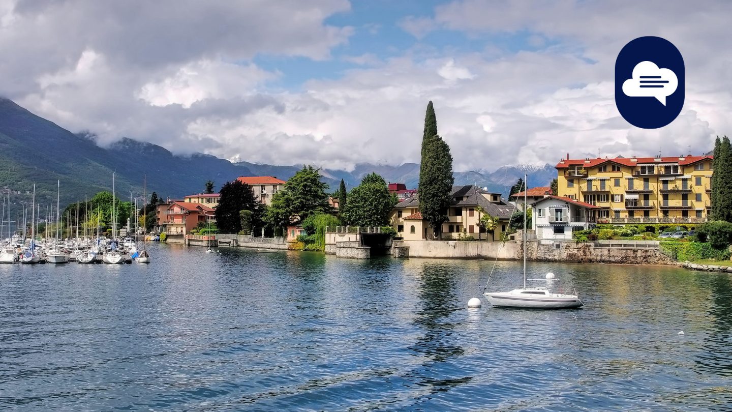 Blick auf Bellano am Comer See in Mailand mit Segelbooten, bunten Häusern und Bergen im Hintergrund