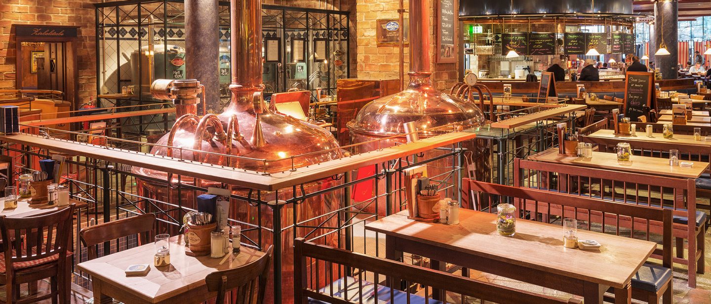 Rustikales Brauhaus-Interieur mit glänzenden Kupferkesseln und Holztischen