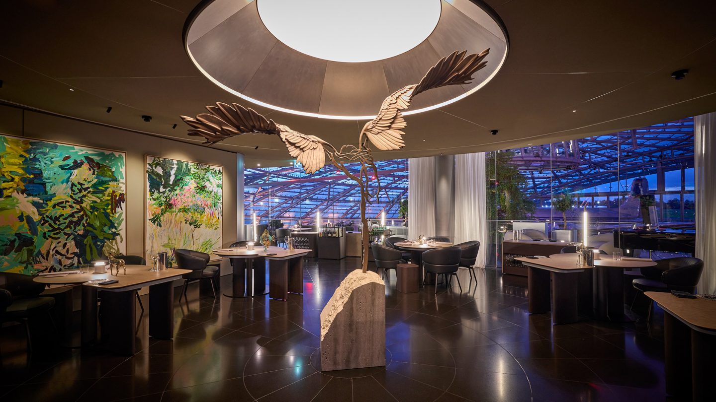 Modernes Restaurant Ikarus im Hangar-7 mit einer großen Vogelskulptur und bunter Kunst