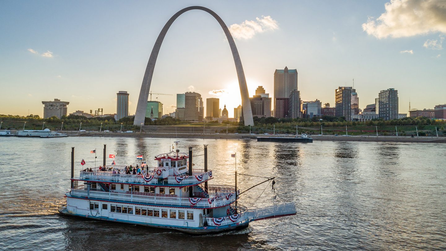 Dampferfahrt auf dem Mississippi mit dem Gateway Arch und der Skyline von St. Louis bei Sonnenuntergang.