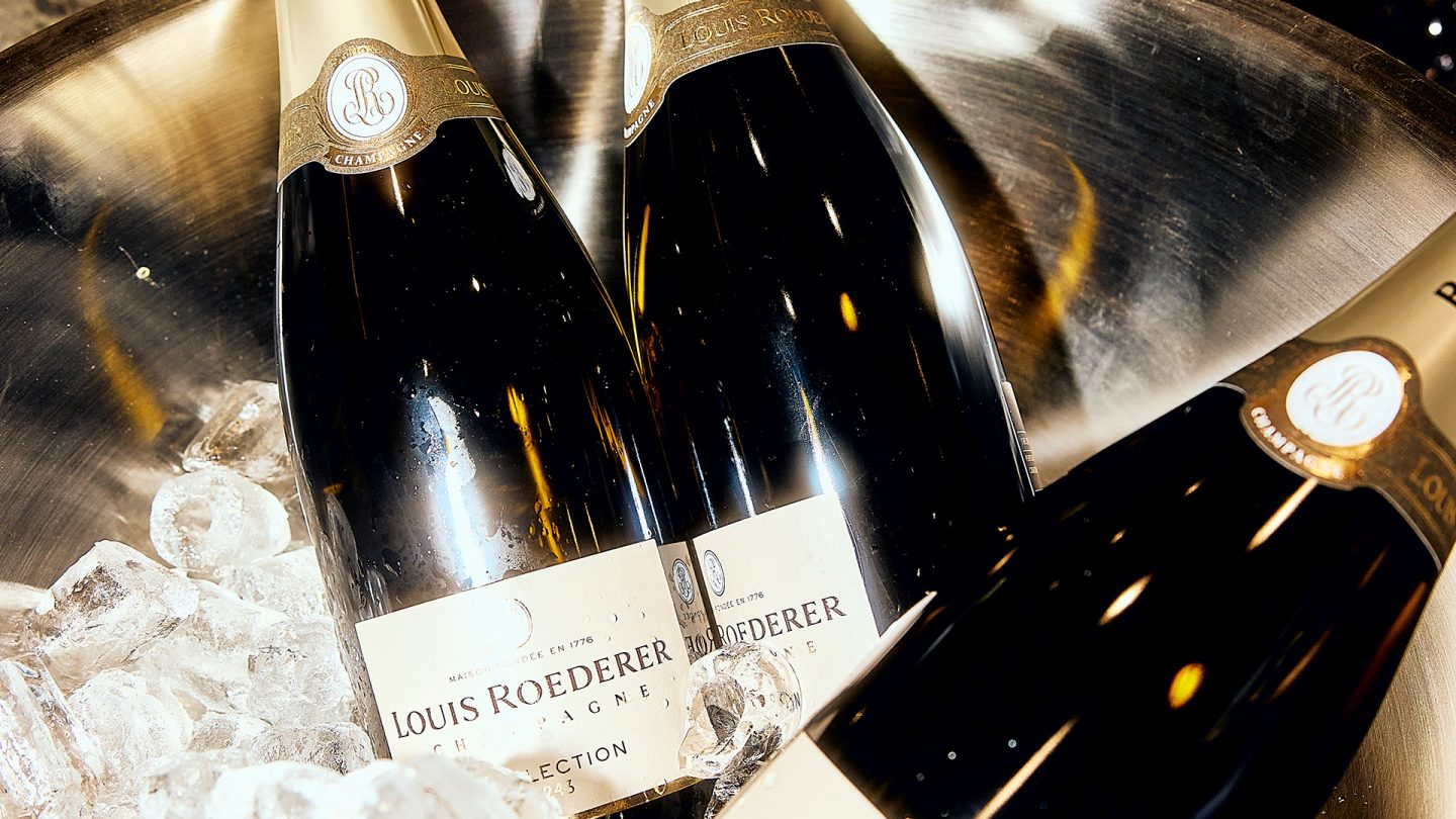 Mehrere Champagnerflaschen in einer Schale mit Eis, Etikett „Louis Roederer“ sichtbar.