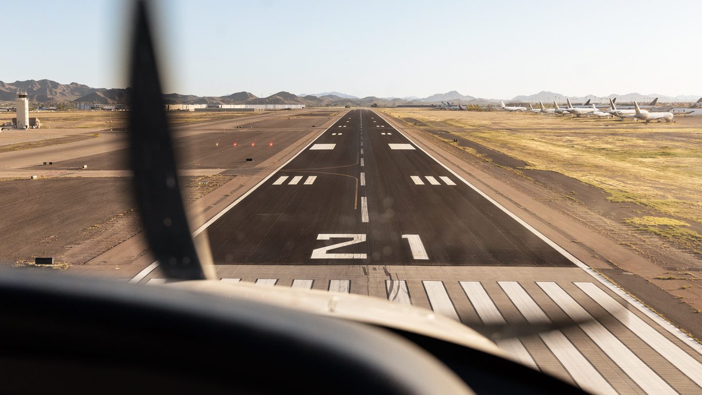 Blick aus dem Cockpit eines Flugzeugs kurz vor der Landung auf eine asphaltierte Landebahn.