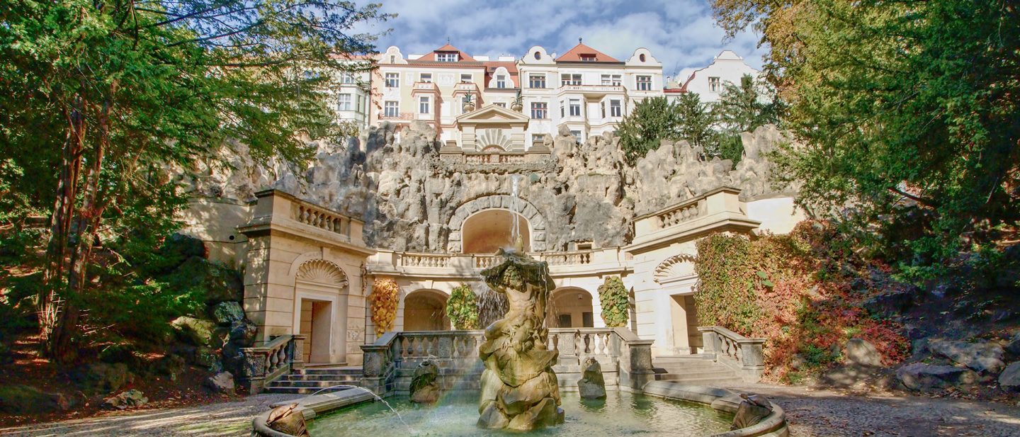 Brunnen mit Statue vor barockem Palais im Wallenstein-Garten