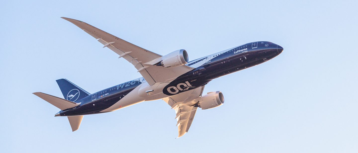 Ein weiß-blauer Lufthansa-Boeing fliegt vor blauem Himmel