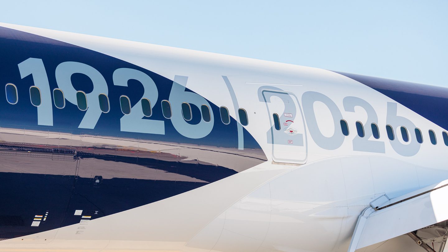 Nahaufnahme der blau-weißen Lufthansa-Lackierung mit den Zahlen „1926” und „2026” vor blauem Himmel