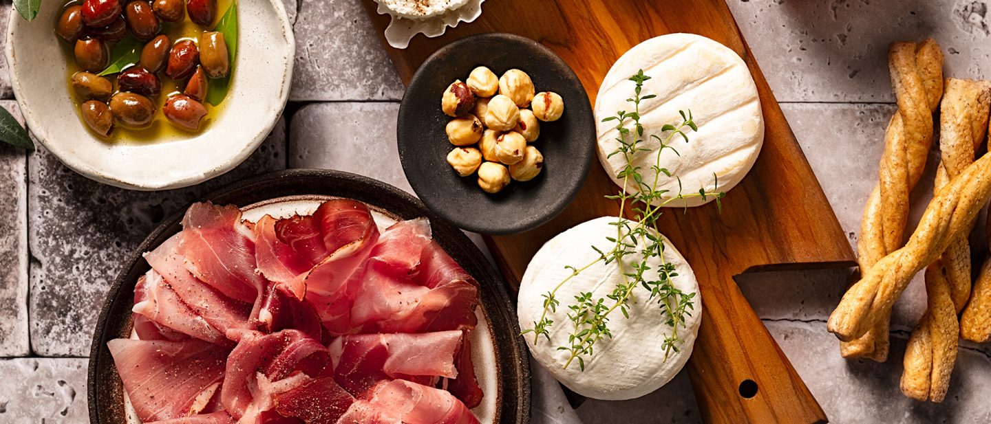 Italienische Antipasti mit Oliven, Nüssen, Käse, Schinken und Brotstangen auf einem gedeckten Tisch