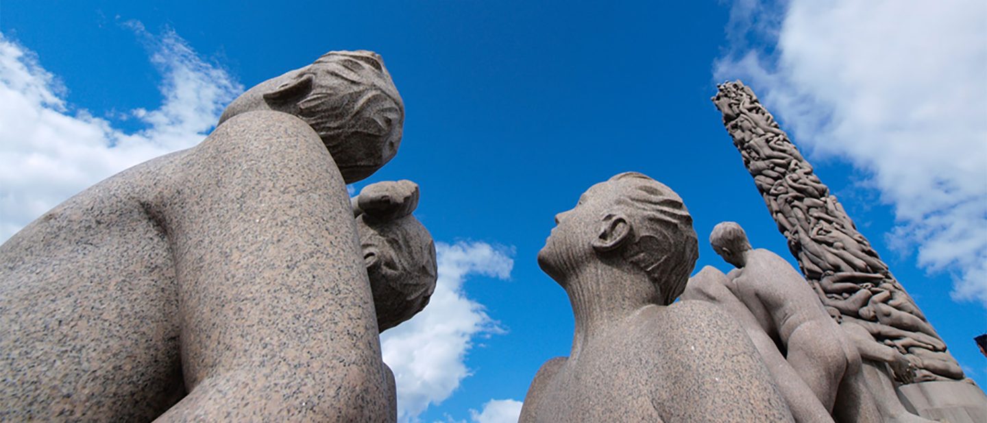 Skulpturen aus dem Vigeland Park in Oslo, die bei blauem Himmel zum hohen Monolithen aufblicken