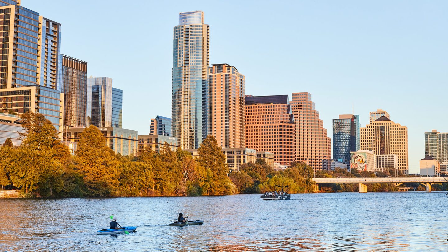 Skyline von Austin bei Sonnenuntergang über dem Colorado River mit Kajaks