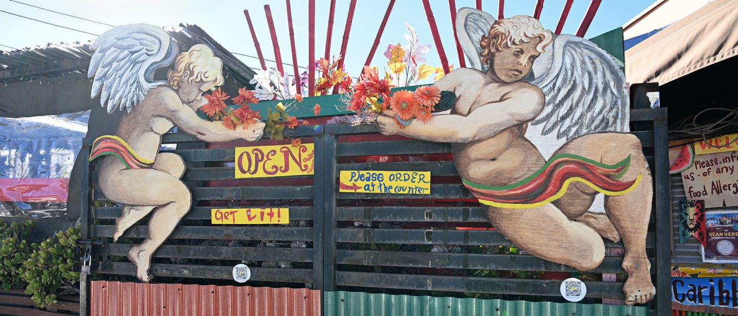 Wandgemälde mit zwei sitzenden Engeln, die Blumen halten, vor einem 'OPEN'-Schild
