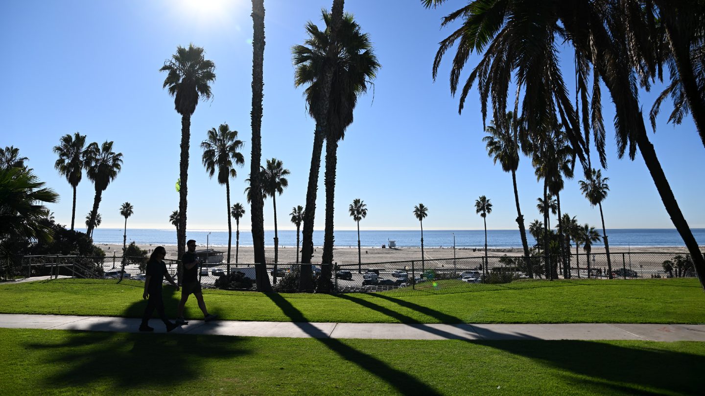 Silhouetten von Palmen und Fußgängern am Strand von Santa Monica