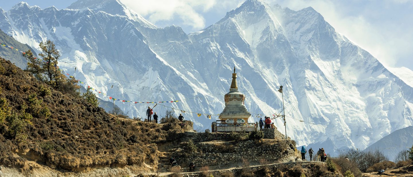 Stupa mit Gebetsfahnen vor schneebedeckten Himalaya-Gipfeln in Nepal