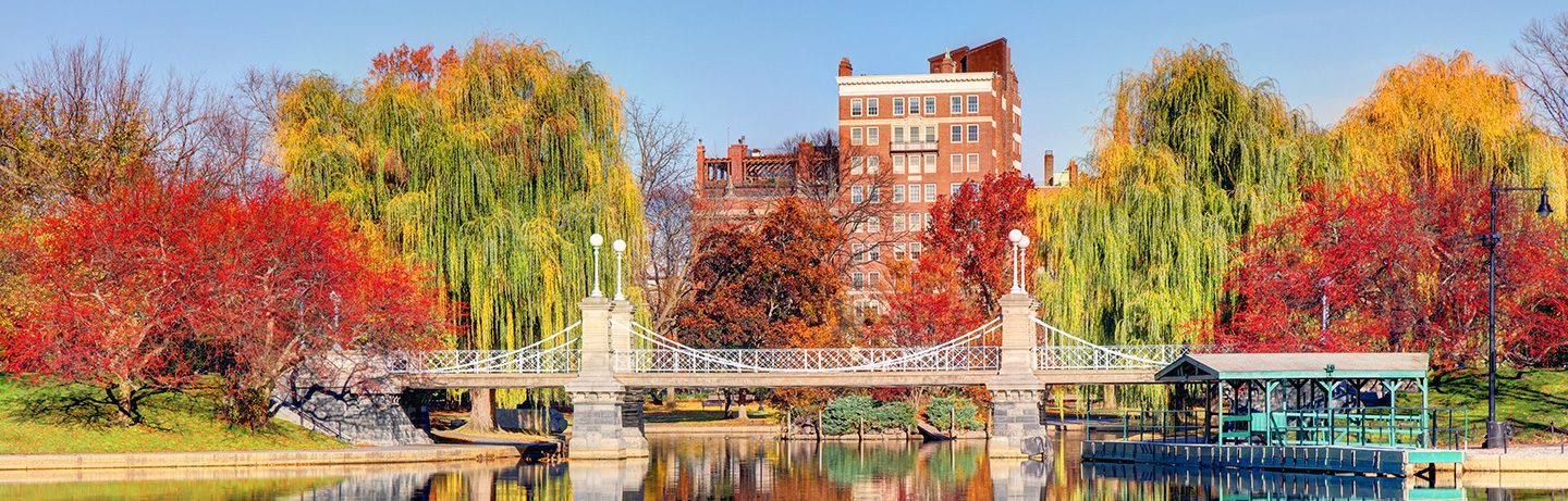 Herbststimmung im Boston Public Garden mit historischer Brücke, leuchtend bunten Bäumen und Spiegelungen im Wasser