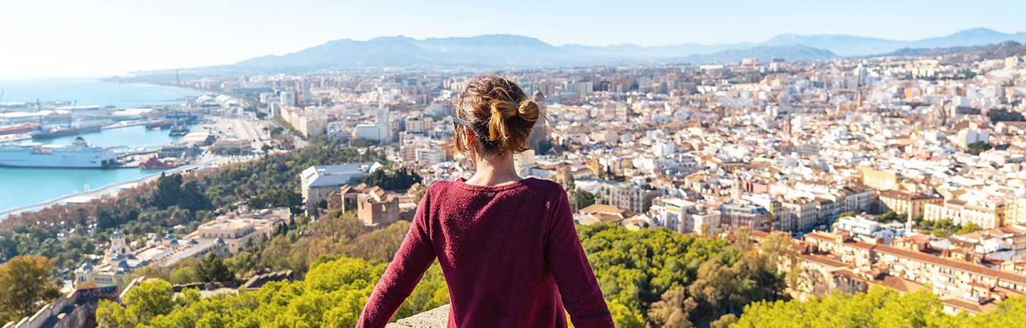 Frau blickt über die Stadt Málaga und den Hafen.